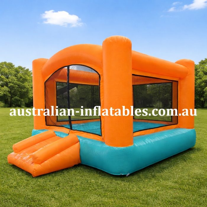 Orange and teal inflatable bounce house on a grassy field in a park, with the URL australian-inflatables.com.au across the front edge.